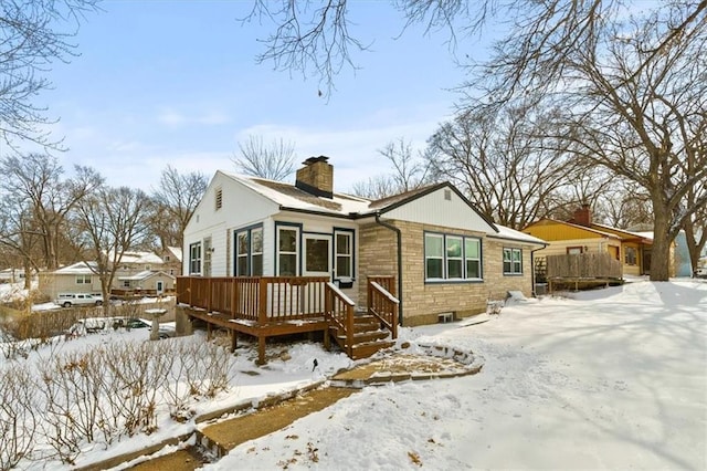 view of front facade featuring stone siding, a chimney, and a wooden deck