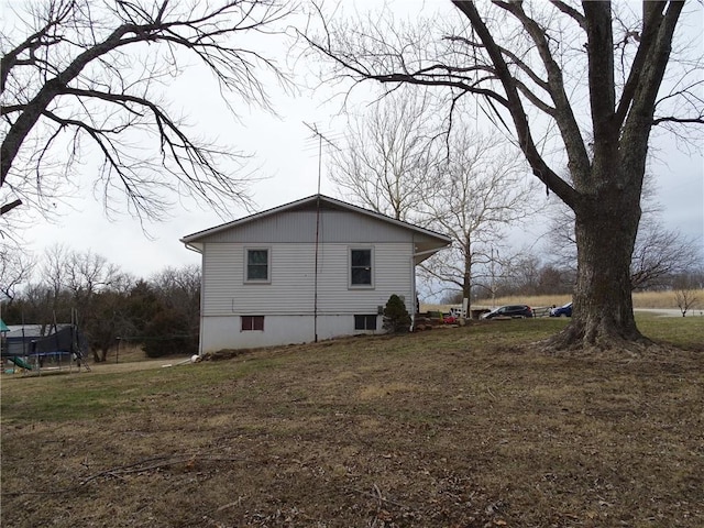 view of home's exterior with a yard and a trampoline