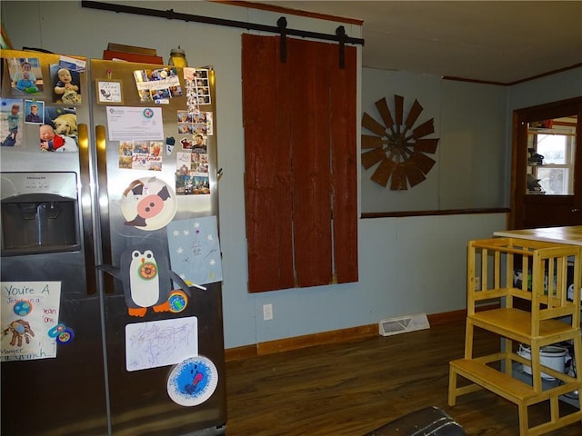 kitchen with a barn door, dark hardwood / wood-style floors, and stainless steel fridge with ice dispenser