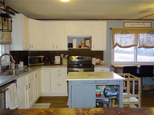 kitchen with sink, dark wood-type flooring, stainless steel appliances, white cabinets, and decorative backsplash