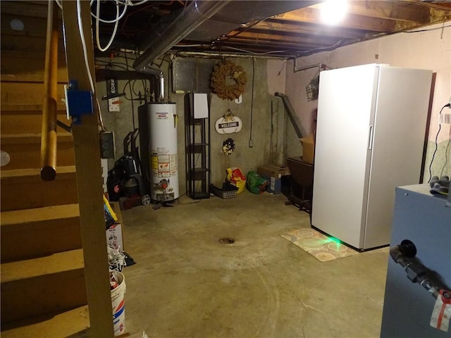 basement with water heater and white refrigerator