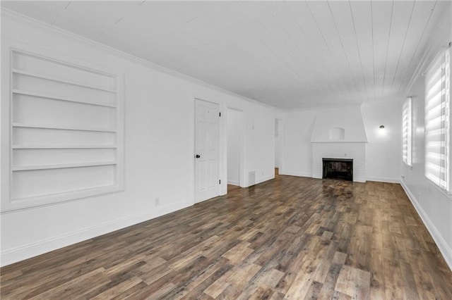 unfurnished living room featuring crown molding, built in shelves, a fireplace, and dark hardwood / wood-style floors