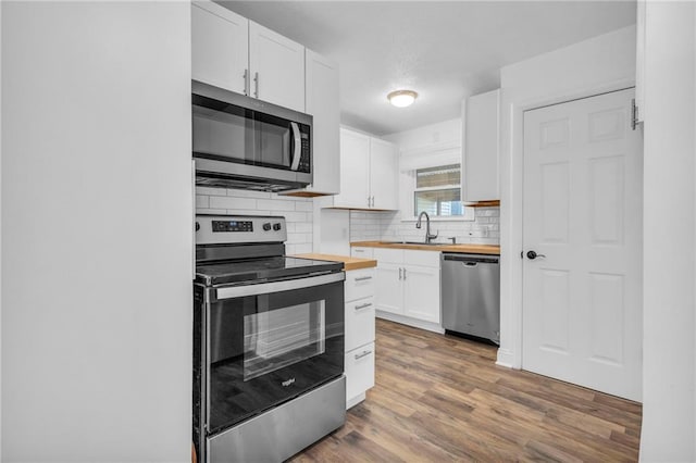 kitchen featuring sink, wooden counters, appliances with stainless steel finishes, white cabinets, and decorative backsplash