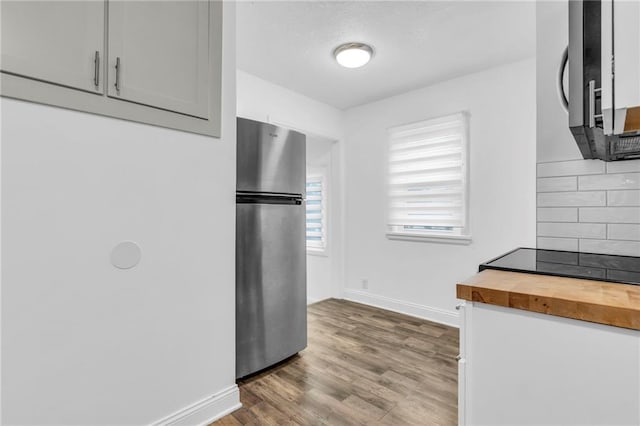 kitchen featuring appliances with stainless steel finishes, butcher block countertops, tasteful backsplash, wood-type flooring, and white cabinets