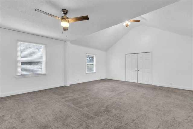 empty room with ceiling fan, vaulted ceiling, carpet, and a textured ceiling