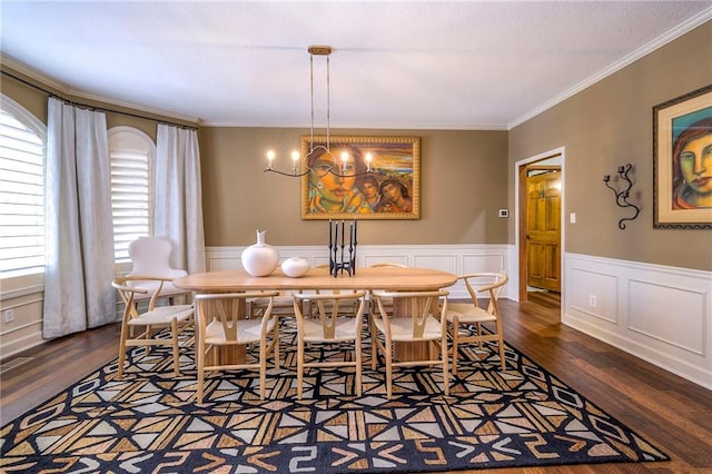 dining area with dark wood-style flooring, a wainscoted wall, crown molding, and an inviting chandelier