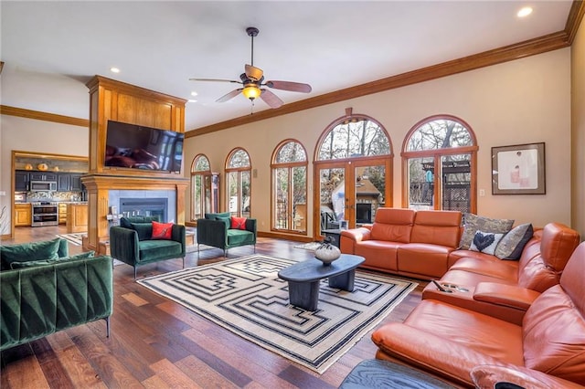 living area featuring a large fireplace, a healthy amount of sunlight, crown molding, and wood finished floors