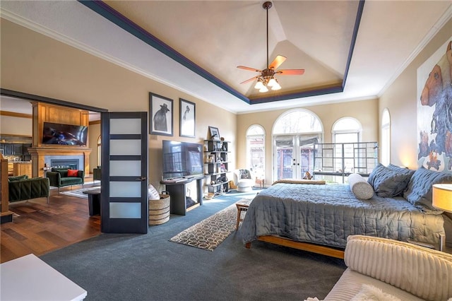 bedroom with a fireplace, carpet flooring, ornamental molding, french doors, and a tray ceiling