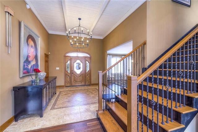 foyer entrance with beam ceiling, baseboards, a notable chandelier, and ornamental molding