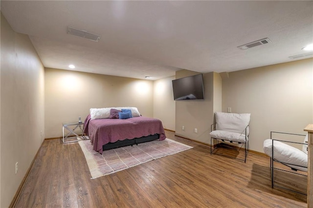 bedroom with baseboards, visible vents, and wood finished floors