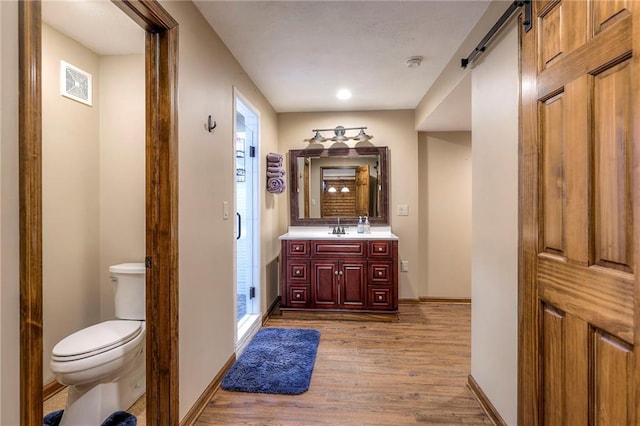 bathroom featuring a stall shower, visible vents, toilet, wood finished floors, and vanity