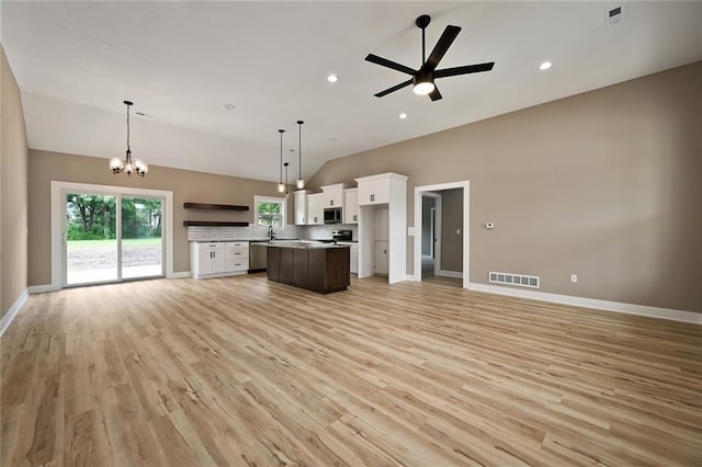 kitchen with white cabinetry, a center island, vaulted ceiling, light wood-type flooring, and pendant lighting