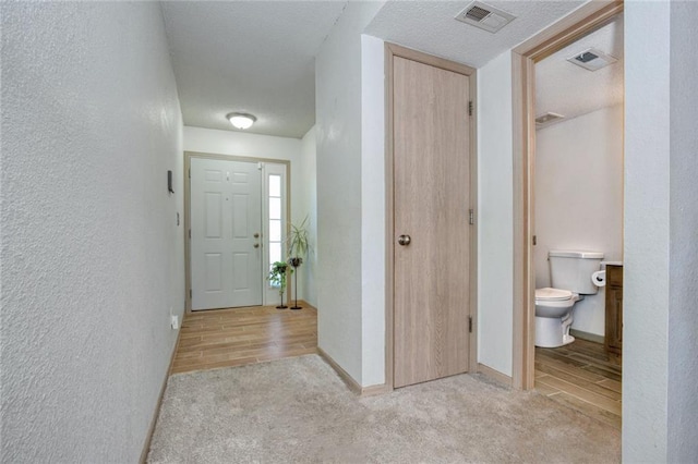 carpeted foyer featuring a textured ceiling