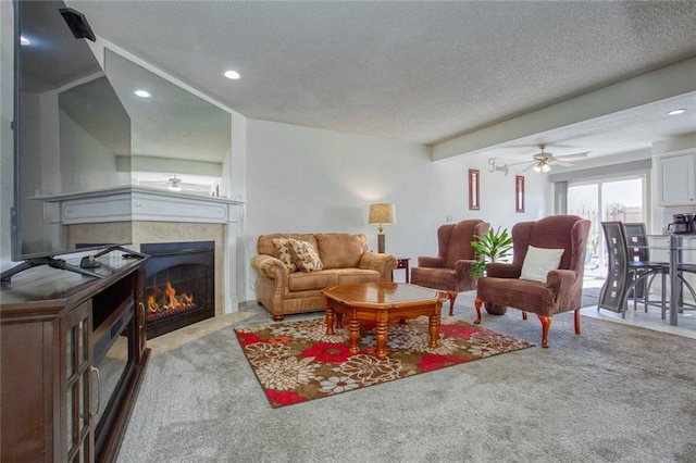 carpeted living room with a tiled fireplace, ceiling fan, and a textured ceiling