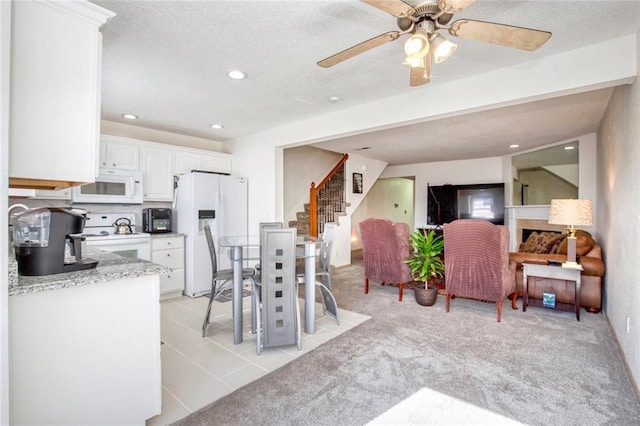 kitchen featuring white appliances, a textured ceiling, ceiling fan, light carpet, and white cabinetry