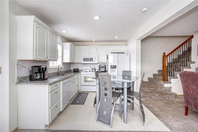 kitchen featuring sink, white appliances, white cabinetry, and tasteful backsplash