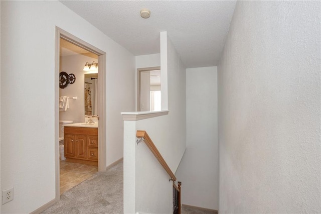 hall featuring sink, light carpet, and a textured ceiling