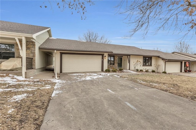 view of front facade featuring stone siding, an attached garage, a shingled roof, and driveway