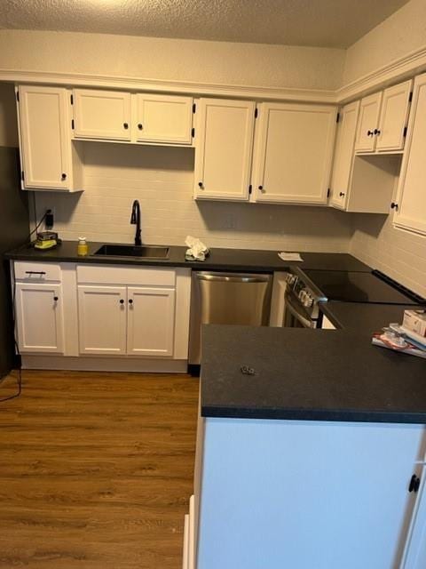 kitchen featuring hardwood / wood-style floors, white cabinetry, sink, stainless steel appliances, and a textured ceiling