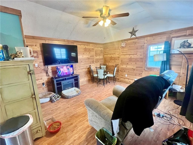 living room with ceiling fan, lofted ceiling, hardwood / wood-style floors, and wood walls