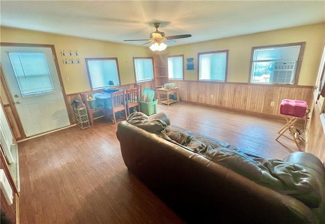 living room featuring vaulted ceiling, cooling unit, wooden walls, hardwood / wood-style flooring, and ceiling fan