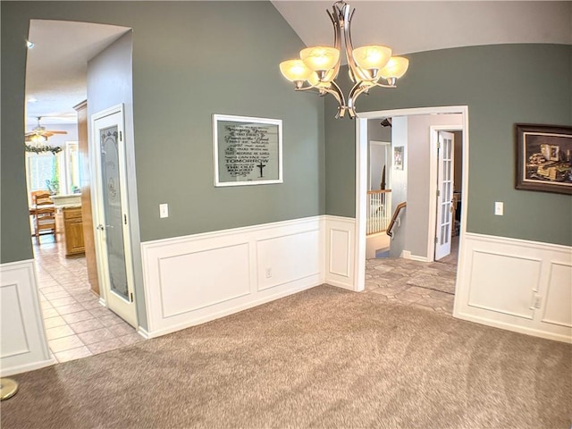 carpeted empty room featuring vaulted ceiling and a notable chandelier