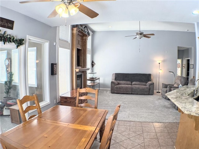 dining room with ceiling fan, vaulted ceiling, light tile patterned floors, and a fireplace