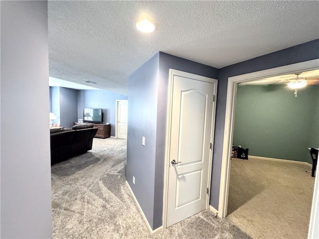 hall with carpet floors and a textured ceiling