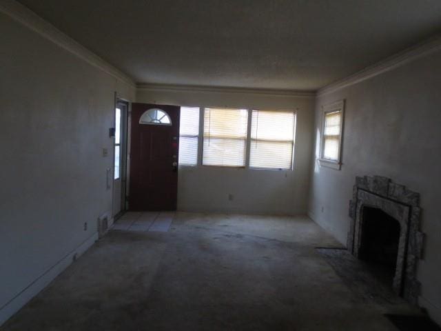 unfurnished living room with crown molding, light colored carpet, and a wealth of natural light