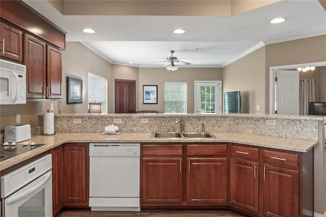 kitchen with crown molding, sink, white appliances, and kitchen peninsula