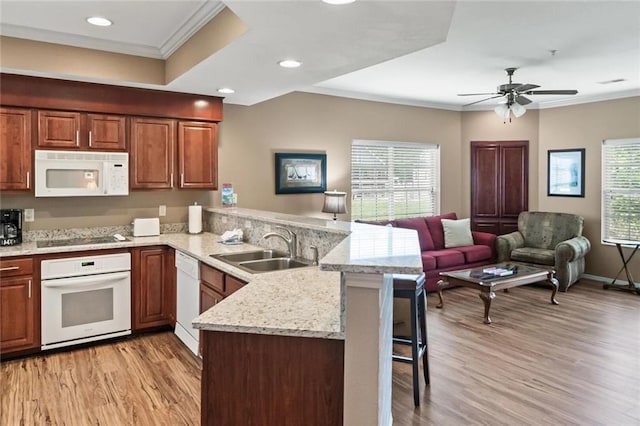 kitchen featuring a kitchen bar, sink, kitchen peninsula, a wealth of natural light, and white appliances