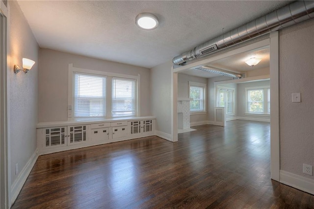 unfurnished room with dark hardwood / wood-style flooring, a textured ceiling, and a wealth of natural light