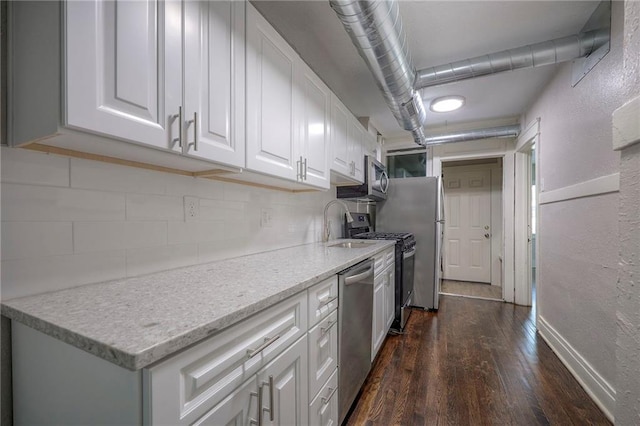 kitchen featuring sink, white cabinetry, dark hardwood / wood-style floors, stainless steel appliances, and decorative backsplash