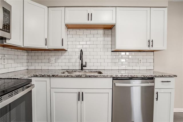 kitchen featuring tasteful backsplash, white cabinetry, sink, stainless steel appliances, and light stone countertops