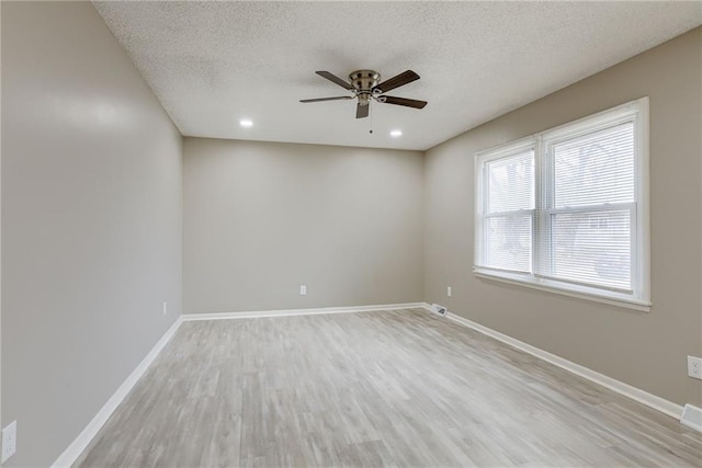 unfurnished room with ceiling fan, a textured ceiling, and light wood-type flooring