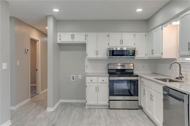 kitchen with light stone countertops, stainless steel appliances, sink, and white cabinets