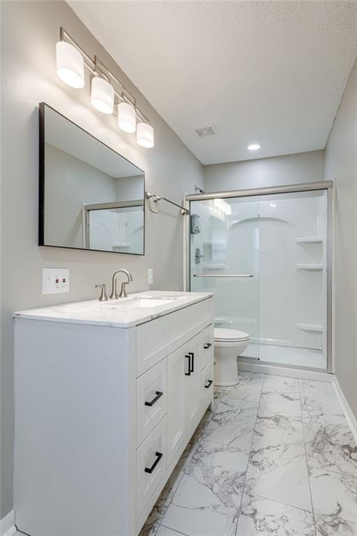 bathroom featuring vanity, a textured ceiling, a shower with shower door, and toilet