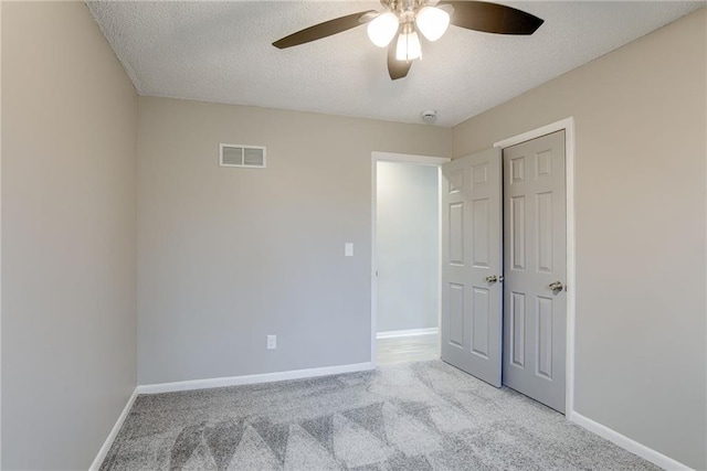 carpeted spare room featuring ceiling fan and a textured ceiling