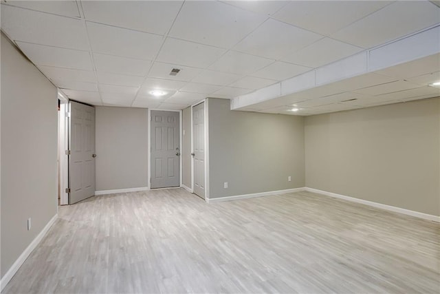 basement with a paneled ceiling and light wood-type flooring