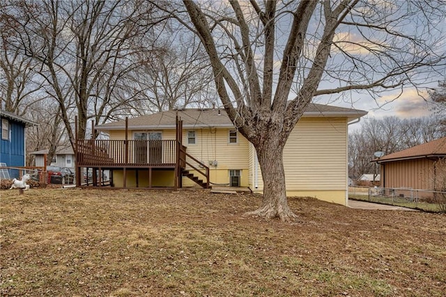 back house at dusk with a wooden deck and a yard