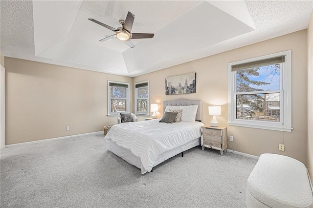 bedroom featuring carpet floors, a raised ceiling, multiple windows, and baseboards