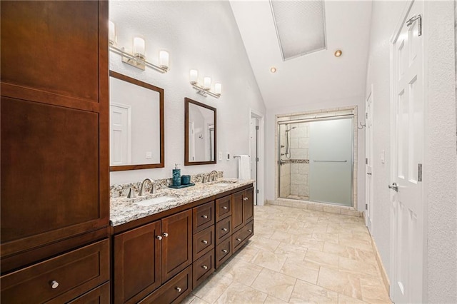 bathroom with double vanity, a shower stall, vaulted ceiling, and a sink