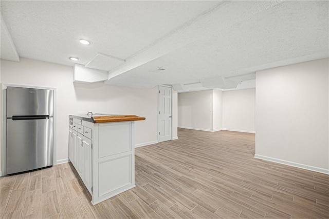 kitchen featuring light wood-style floors, freestanding refrigerator, open floor plan, and white cabinetry