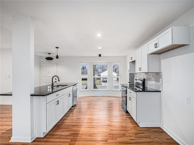 kitchen with sink, stainless steel appliances, light hardwood / wood-style floors, white cabinets, and decorative backsplash