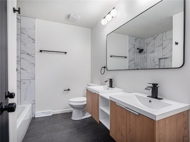 full bathroom featuring tiled shower / bath, vanity, toilet, and a textured ceiling