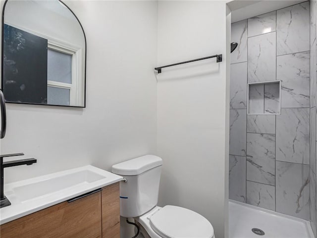 bathroom featuring vanity, toilet, and tiled shower