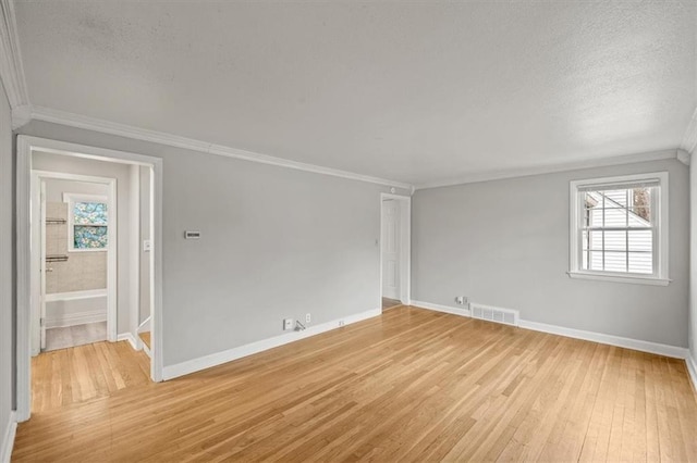 spare room with ornamental molding, a healthy amount of sunlight, a textured ceiling, and light wood-type flooring