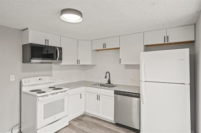 kitchen with sink, light wood-type flooring, white cabinets, stainless steel appliances, and backsplash