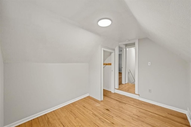 bonus room with light hardwood / wood-style flooring and vaulted ceiling