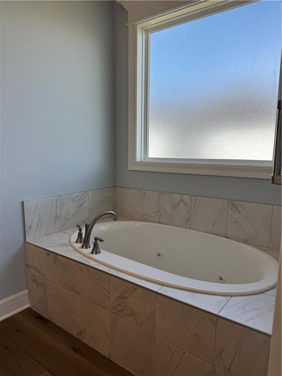 25297 W 149th Ter, Olathe, KS 66061 - bathroom featuring wood finished floors, a whirlpool tub, and baseboards